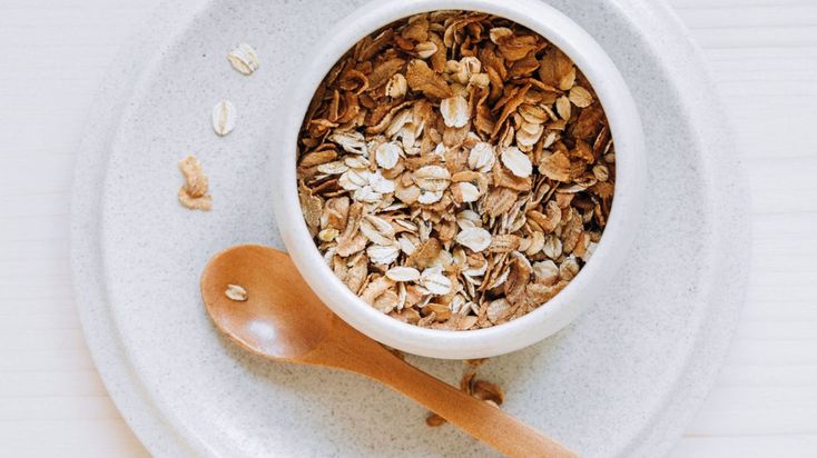 an oatmeal in a bowl on a white plate with a wooden spoon