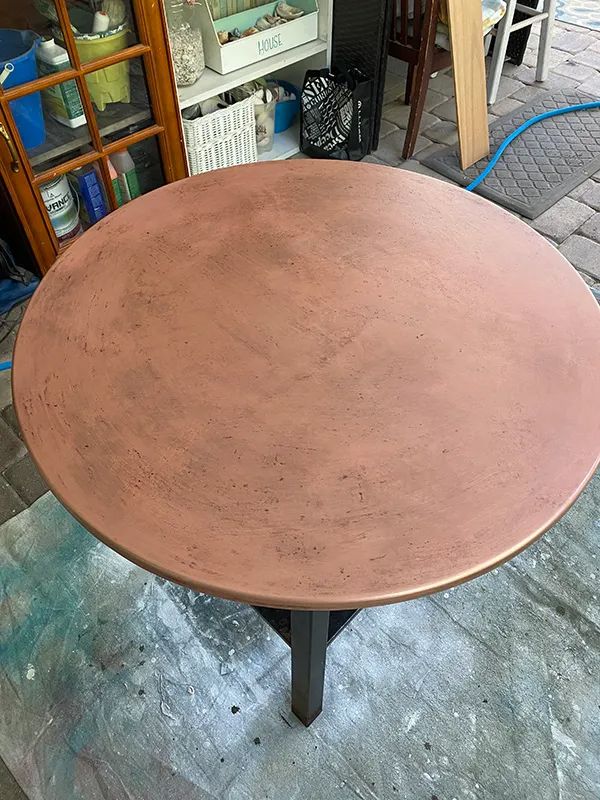 a round metal table sitting on top of a floor next to a store front window