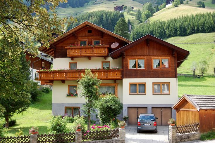 a car is parked in front of a large house on the side of a road