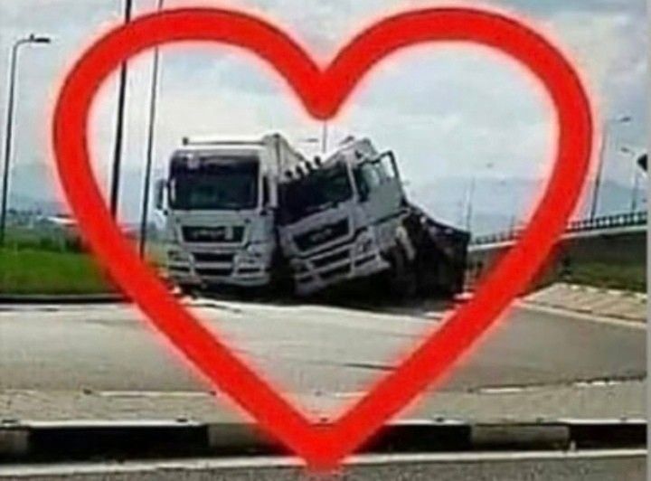 two trucks in the middle of a road with a red heart shaped frame over them