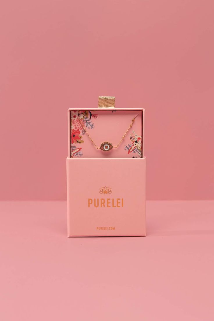 a pink box with a necklace and earrings in it on a pink background that says pureli