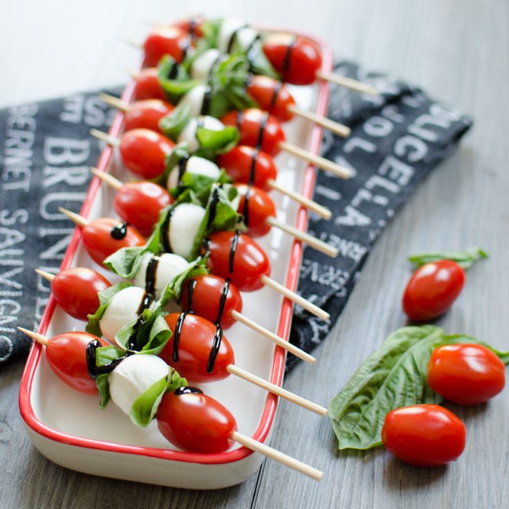 several skewered tomatoes and mozzarella on toothpicks with basil leaves