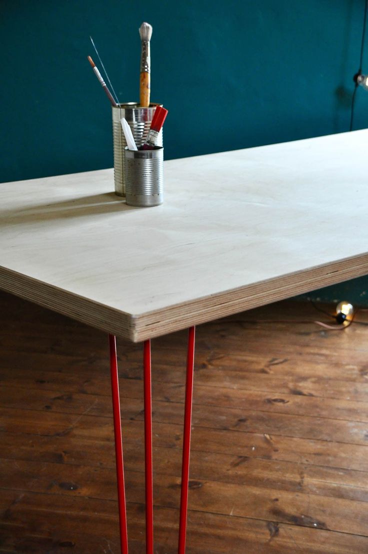 a white table with red legs and paintbrushes on it