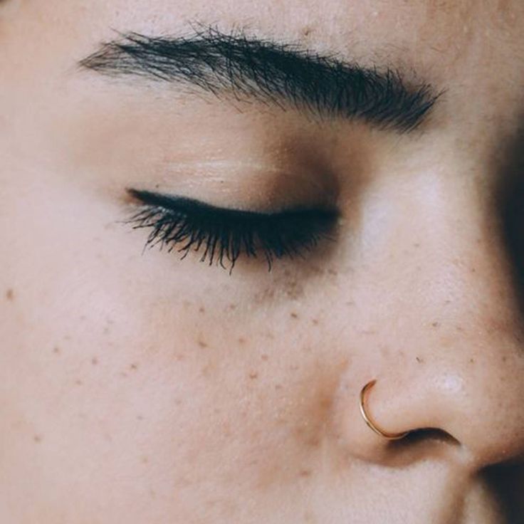 a close up of a woman's face with her nose ring in the middle