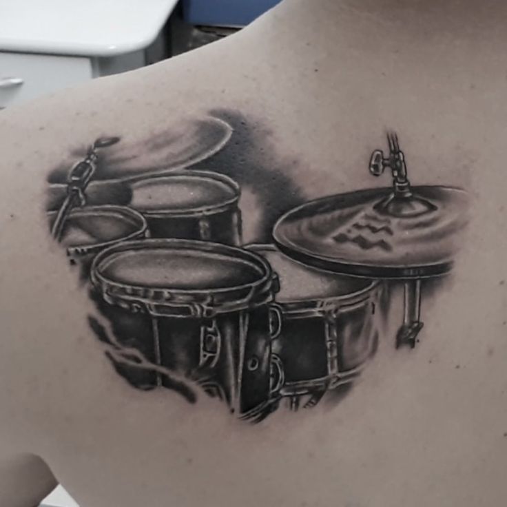 a man with a tattoo on his back has a drum set in front of him