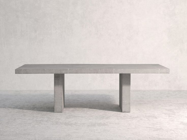 a concrete table sitting on top of a white floor next to a gray wall with no one around it