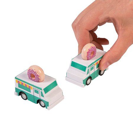 a hand is holding a donut on top of a toy bus that has doughnuts in it