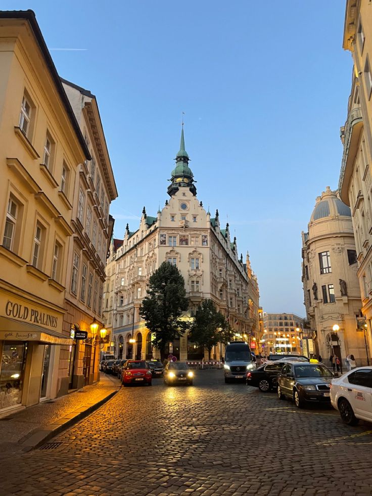 cars parked on the side of a cobblestone street in an old european city