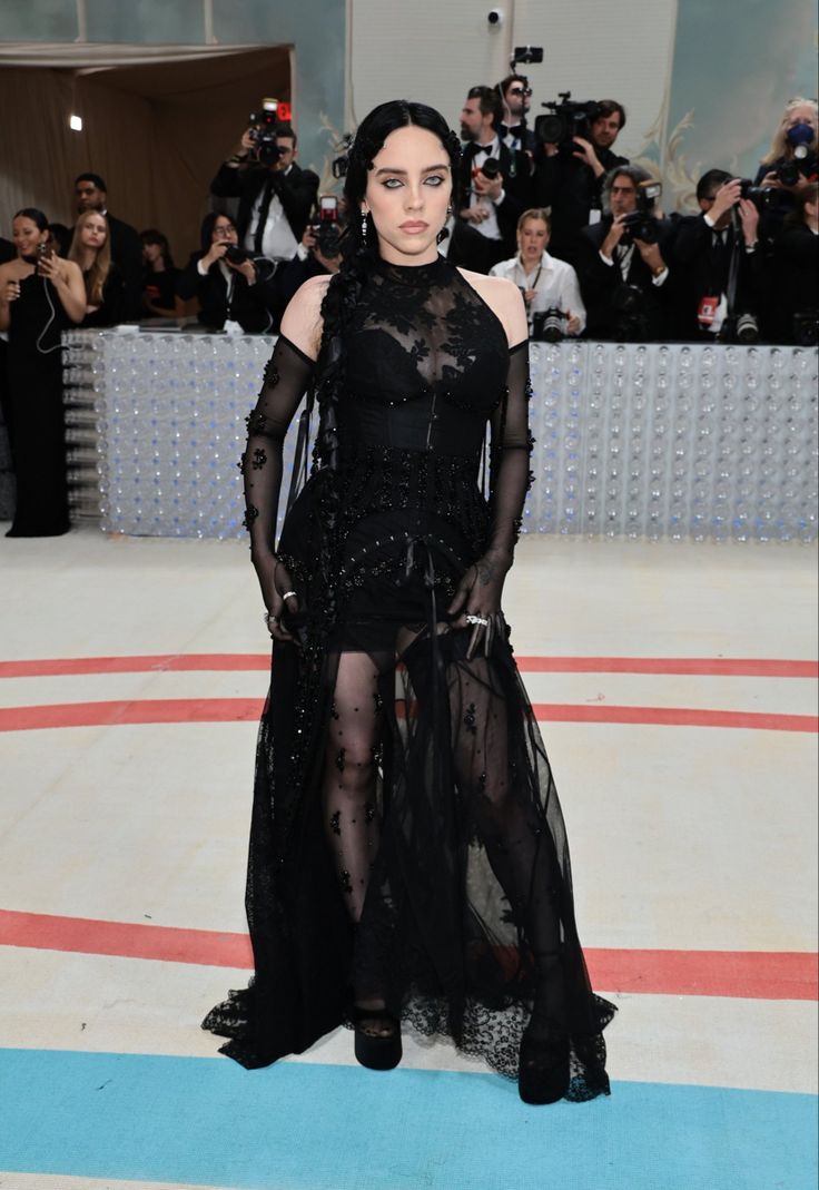 a woman in a black dress standing on a blue and white floor with cameras around her