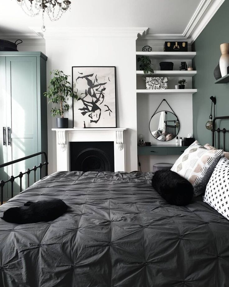 a black and white bed in a bedroom next to a fireplace with lots of shelves