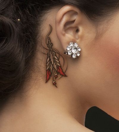 a woman's ear is decorated with flowers and leaves, while the other side has a feather on it