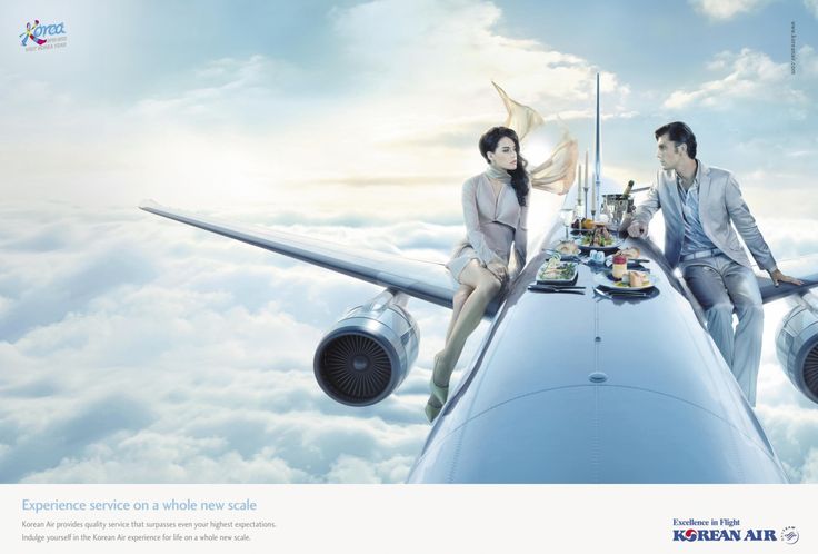 two people sitting on the wing of an airplane with food and drinks in front of them