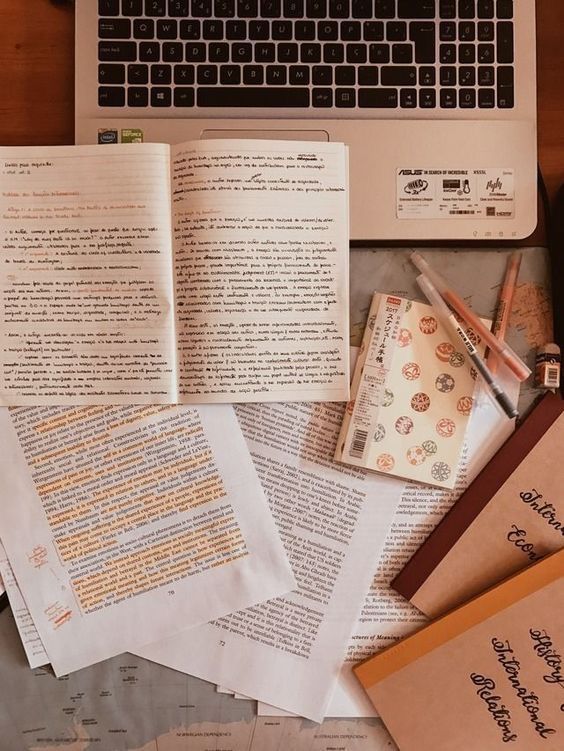 a laptop computer sitting on top of a wooden desk next to papers and pencils