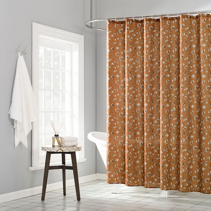 a bath room with a shower curtain next to a tub and a chair in front of a window