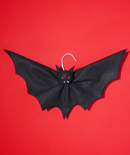 a black bat hanging on a red wall