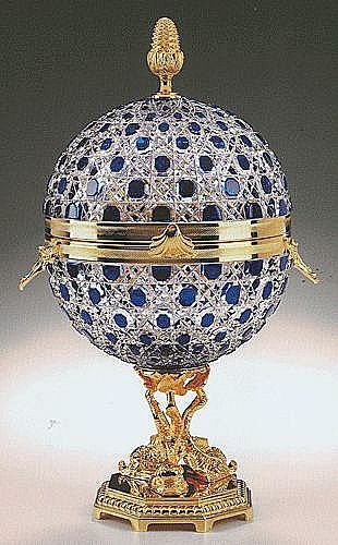 an ornate blue and white ball with gold trimmings on the top, sitting on a stand