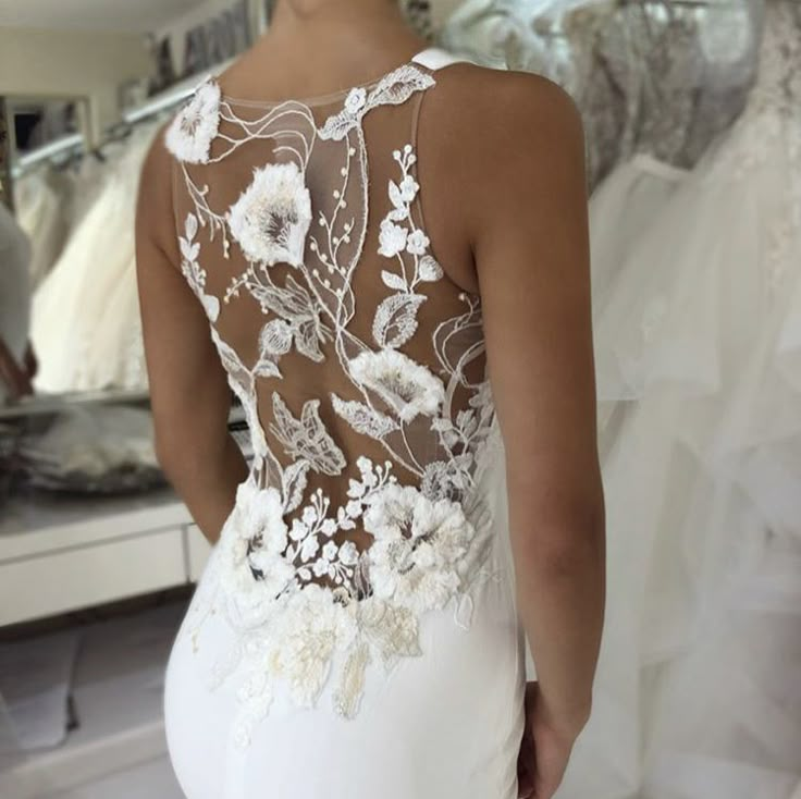 the back of a woman's wedding dress in front of a mirror