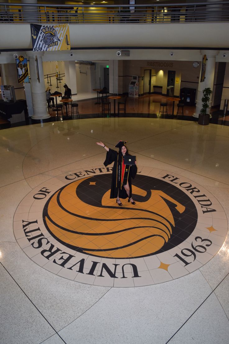 a woman standing in the middle of a large circular floor with an emblem on it