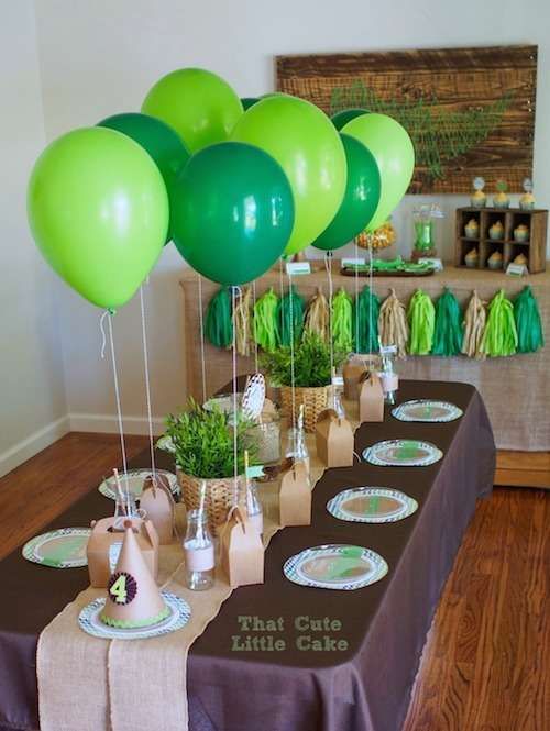 a table topped with lots of green balloons and desserts on top of tables covered in brown paper