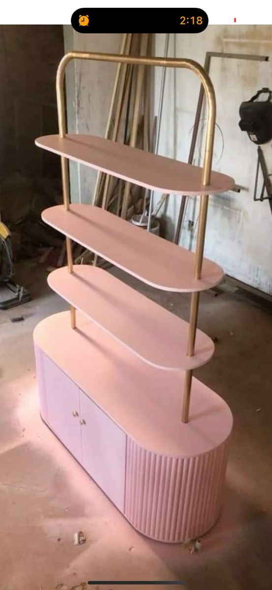 three tiered pink and gold shelf in a garage