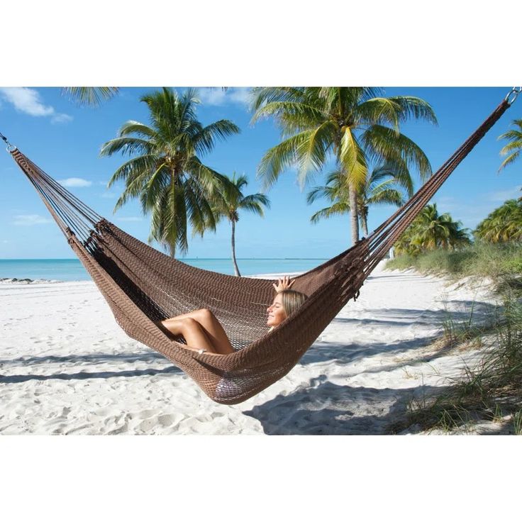 a woman laying in a hammock on the beach