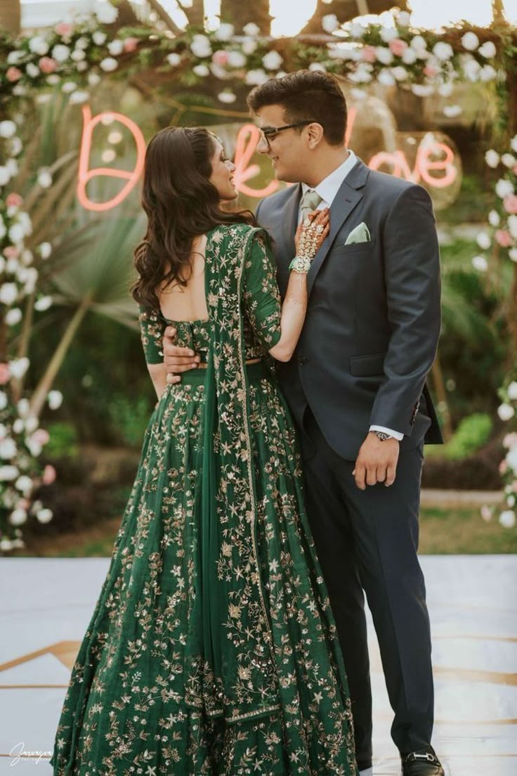 a man and woman standing next to each other in front of a flower covered archway