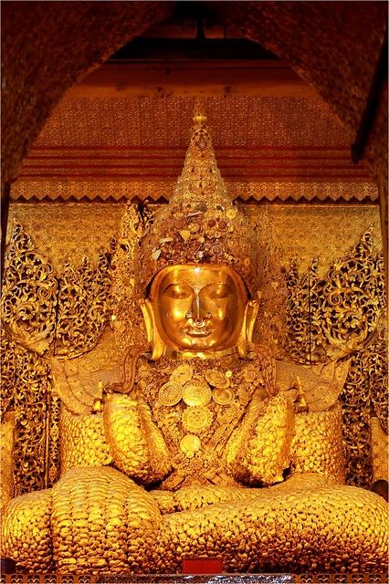 a golden buddha statue sitting in front of a wall