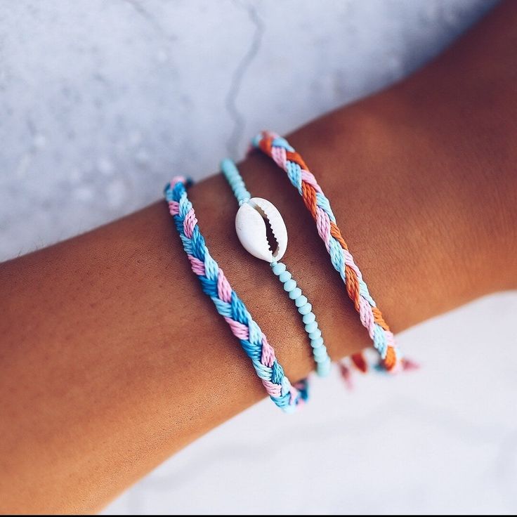 two bracelets that have shells on them, one is blue and the other is pink