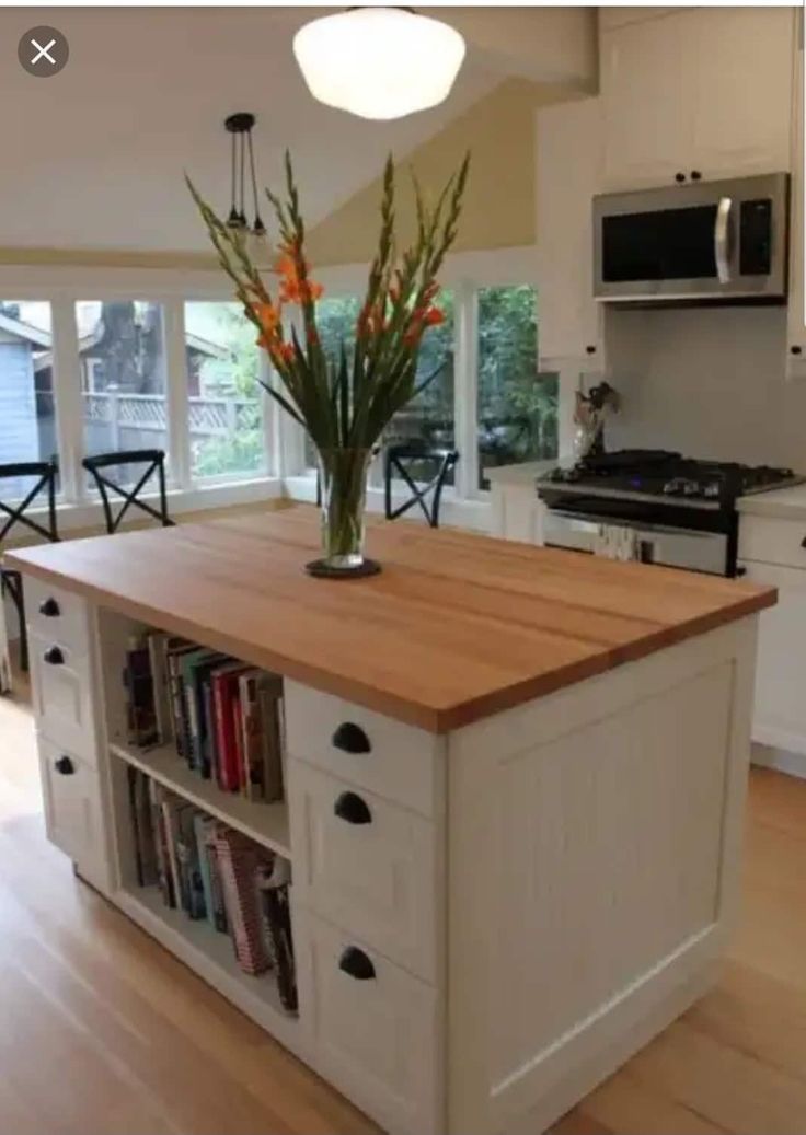 a kitchen island with bookshelves in the middle and flowers on top, next to an oven