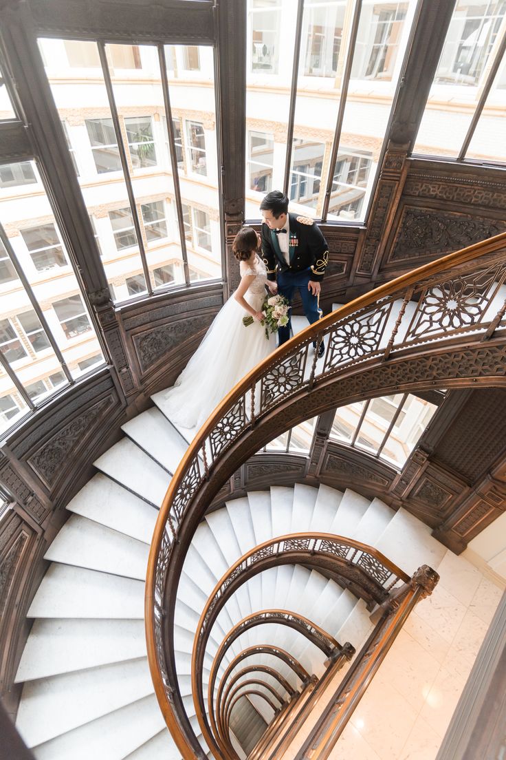 the bride and groom are walking down the stairs at the top of the spiral staircase