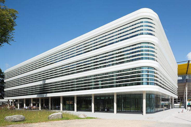 an office building with many windows and people walking around the outside area in front of it