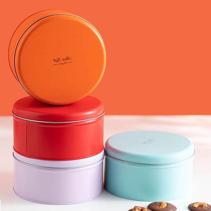 three round tins sitting on top of each other with nuts in front of them