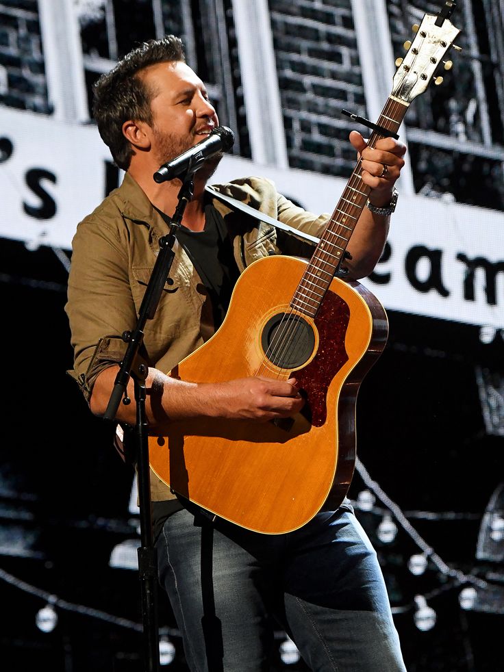 a man holding a guitar and singing into a microphone