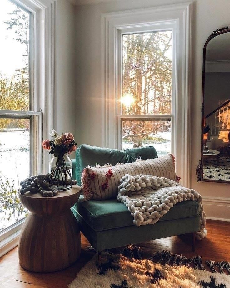 a living room filled with furniture next to a large window covered in blankets and pillows