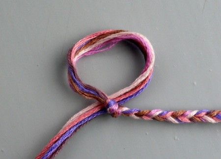 a pink and purple colored rope on a gray surface with one end twisted up to the side