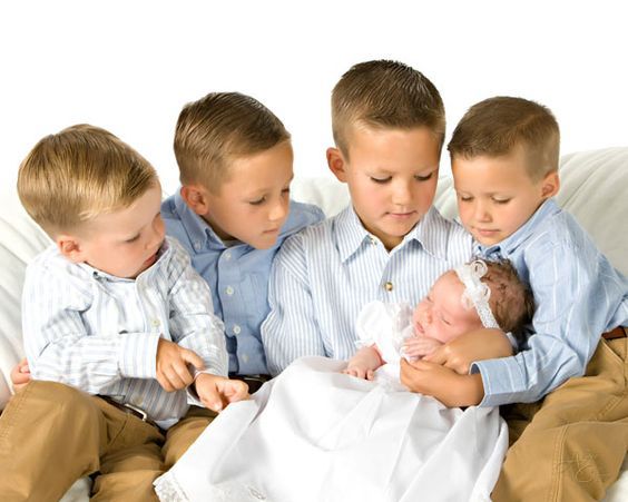 three boys are sitting on a couch with their babies