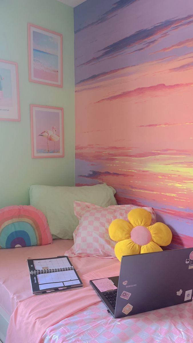 a laptop computer sitting on top of a bed next to pillows and pictures above it