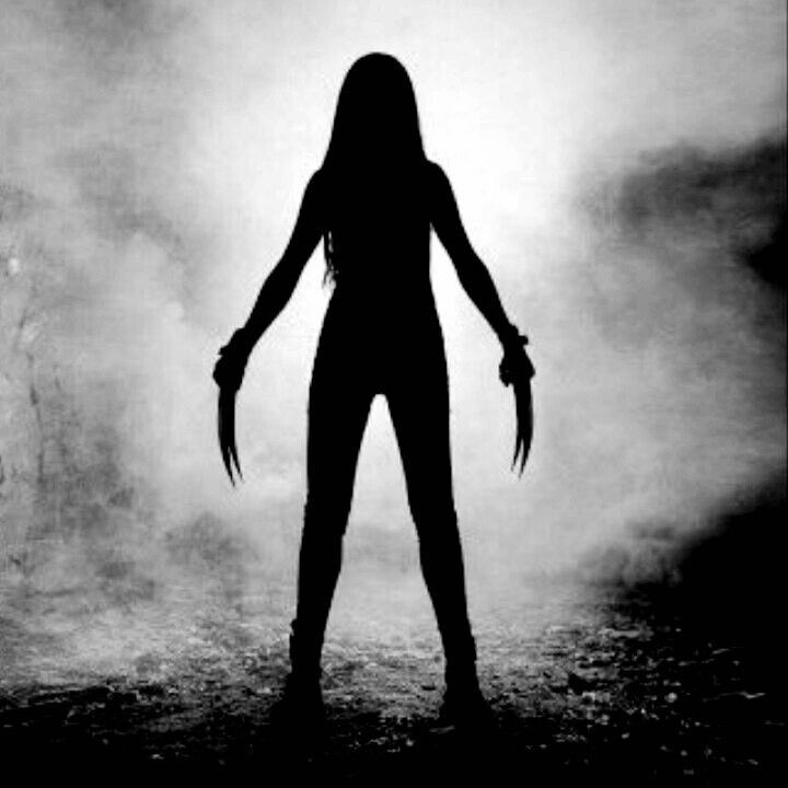 a woman standing in the fog with her arms spread out and hands extended, holding two knives