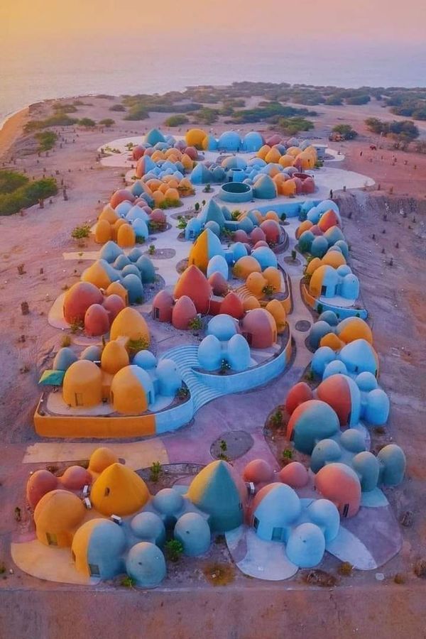 an aerial view of colorfully colored tents on the beach at sunset or sunrise, with water in the background