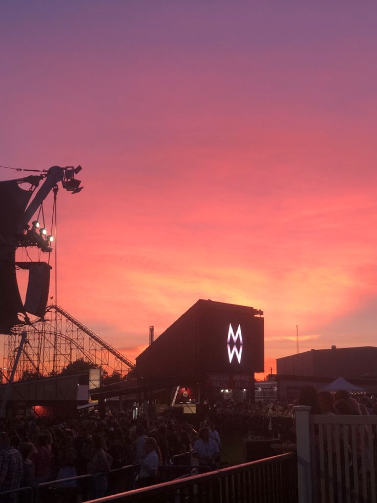 the sun is setting at an outdoor music festival