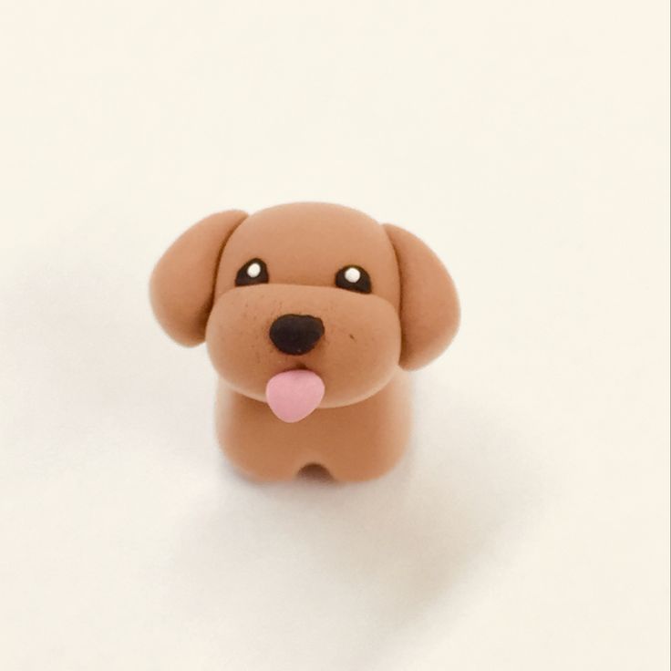 a toy dog with its tongue out sitting on a white surface and looking at the camera