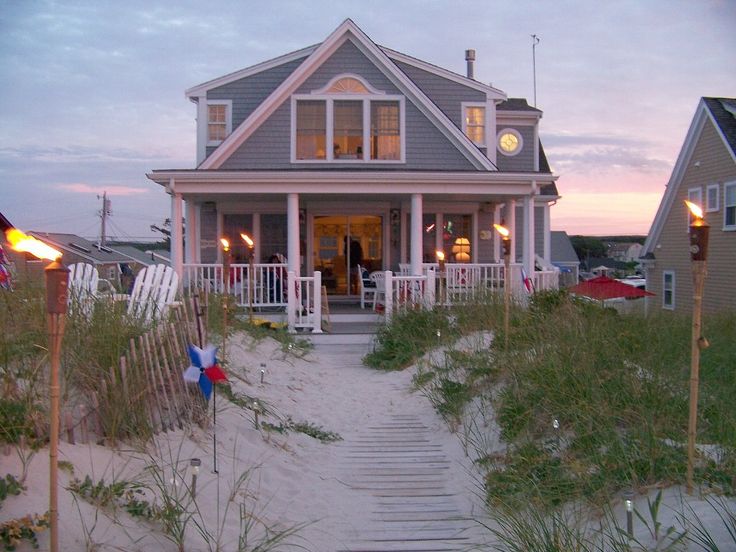 a house on the beach with stairs leading up to it's front door and porch