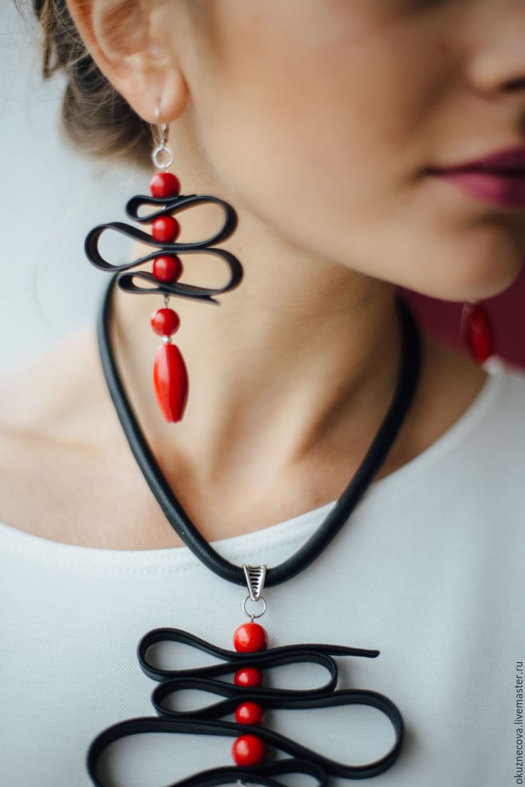 a woman wearing a black and red necklace with an intricate design on the back of it