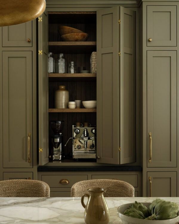 a kitchen with green cabinets and white marble counter tops, including a coffee maker in the corner