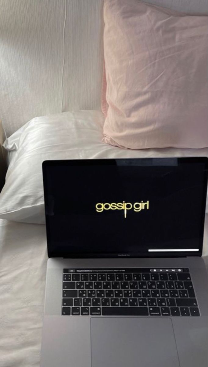 an open laptop computer sitting on top of a bed next to pillows and pillow cases