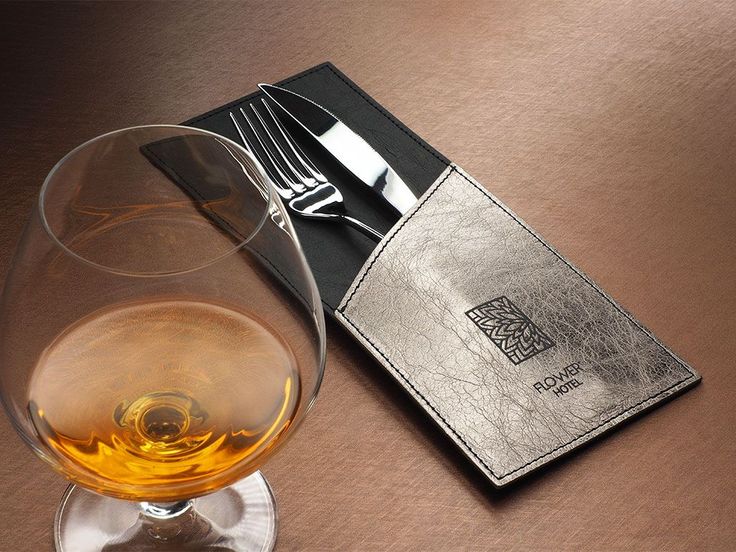 a glass of wine next to a silver fork and knife on a brown table top