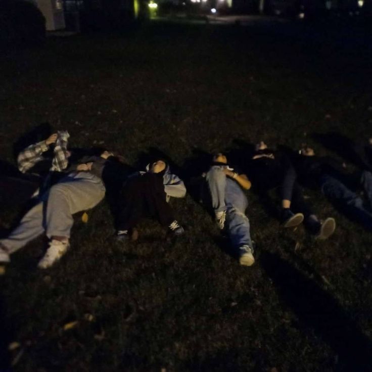 several people laying in the grass at night