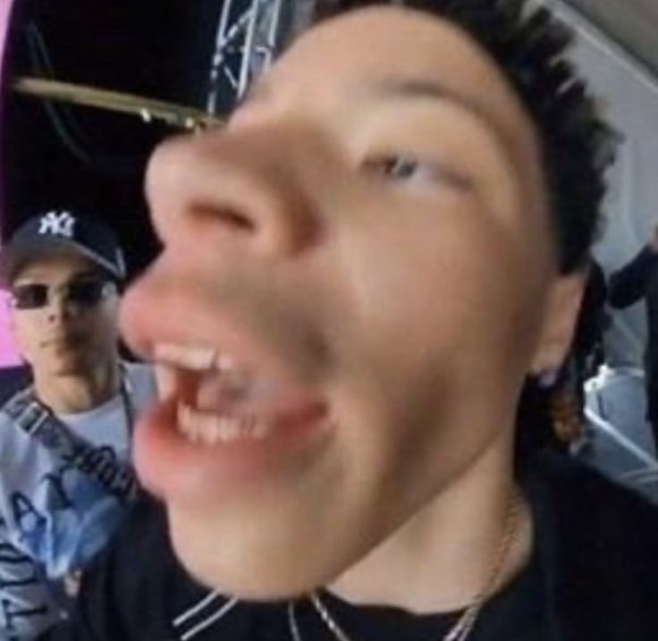 a man with his mouth open and another person in the background taking a selfie