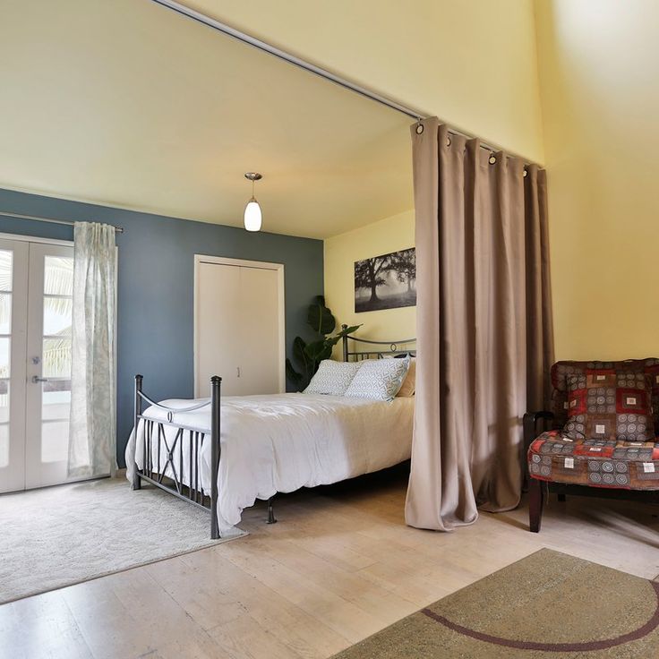 a bedroom with a bed, chair and red curtains