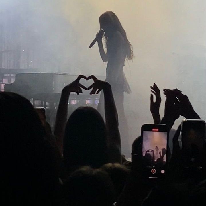 a woman standing on top of a stage with her hands in the air while holding a microphone